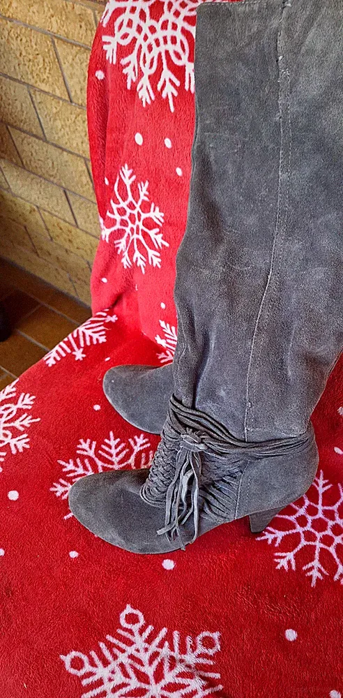 Es handelt sich um graue Wildlederstiefel im Overknee-Stil mit dekorativen Frans